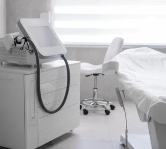 Sala de tratamiento médico con camilla blanca y dispositivo estético avanzado.